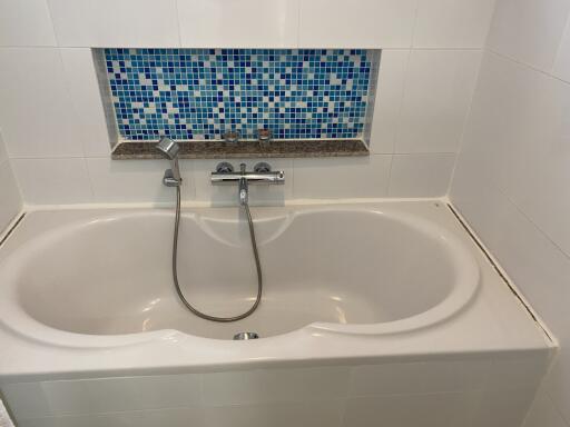 Bathroom with white bathtub and blue tile accent