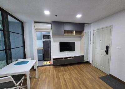 Modern living room with wooden flooring, wall-mounted TV, and integrated storage cabinets