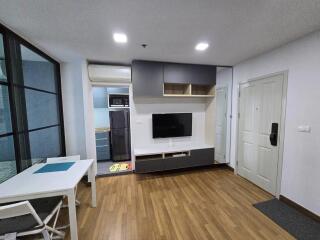 Modern living room with wooden flooring, wall-mounted TV, and integrated storage cabinets