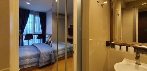 Bedroom with attached bathroom featuring large window and mirrored wardrobe