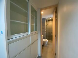 Hallway leading to a bathroom with shelving on the left