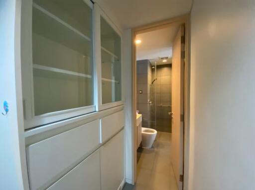 Hallway leading to a bathroom with shelving on the left