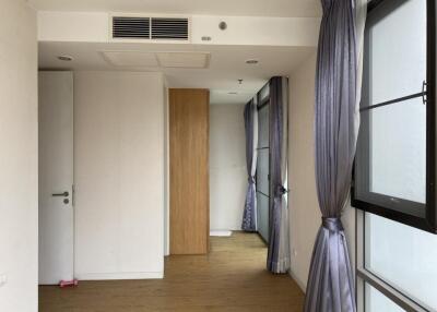 Empty bedroom with wooden floor and large windows with purple curtains