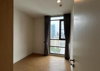 A bedroom with a window and view of the city