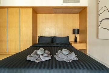 Modern bedroom with black bedding and decorative towels on the bed