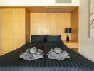 Modern bedroom with black bedding and decorative towels on the bed