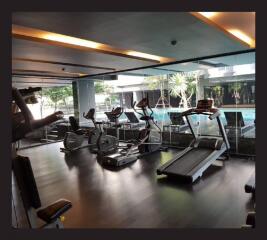 Modern gym with exercise equipment near indoor pool