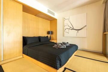 Minimalist bedroom with black bed linens and modern artwork