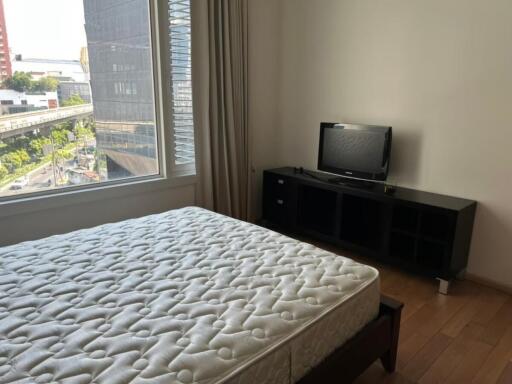 Bedroom with a large window, bed and television