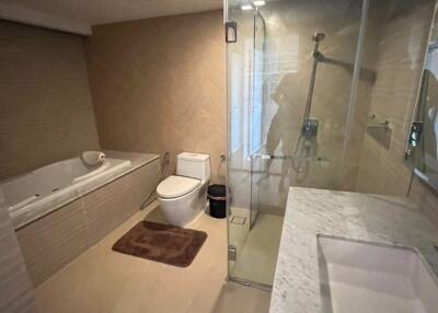 Modern bathroom with glass shower, bathtub, toilet, and marble countertop