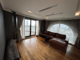 Spacious living room with leather sofa, large windows, and wooden flooring