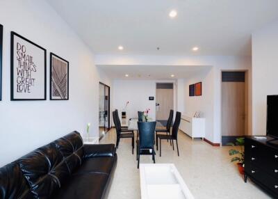 Modern living room with black leather sofa, dining table, and wall art