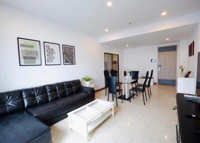 Modern living room with black leather sofa, glass dining table, and decorative wall art