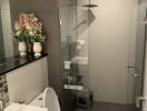 Modern bathroom with shower, toilet, sink, and decorative flowers