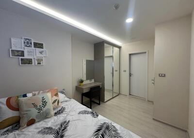 Modern bedroom with a bed, decorative pillows, wall art, desk, and mirrored closet