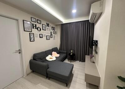 Cozy living room with wall art, gray sofa, TV, and air conditioner