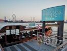 Watermark Pier by the river with boats, ferris wheel, and city skyline in the background