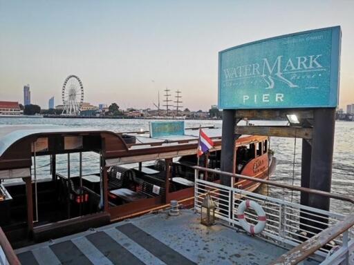 Watermark Pier by the river with boats, ferris wheel, and city skyline in the background