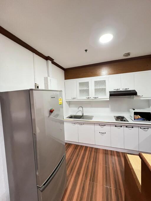 Modern kitchen with wooden flooring and white cabinets