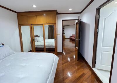 Spacious bedroom with wooden flooring and large mirrored closet doors