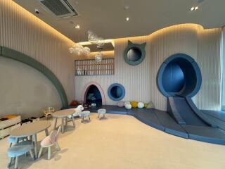 Modern and stylish indoor playroom with various play structures and seating areas.