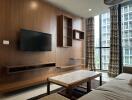 Modern living room with wooden panel wall, TV, shelves, and large windows