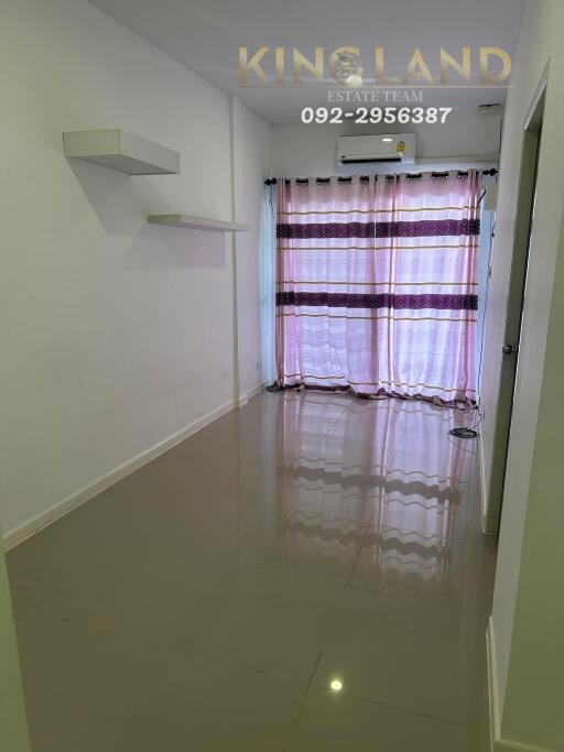 Living room with tiled floor, curtain, and wall shelves