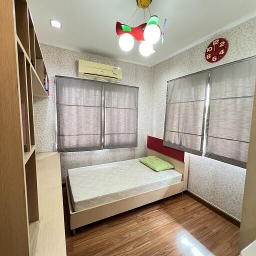 Small bedroom with a single bed, bookshelf, and air conditioning