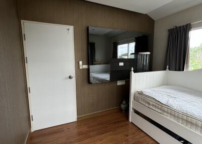 Bedroom with a wooden floor, white door, large mirror, and single bed.