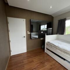 Bedroom with a wooden floor, white door, large mirror, and single bed.