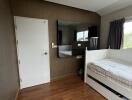 Bedroom with a wooden floor, white door, large mirror, and single bed.