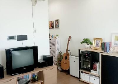 Cozy living room with a TV, wooden flooring, and a guitar