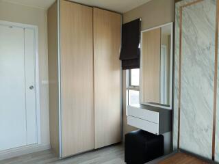 Simple bedroom with a tall wooden wardrobe and a dressing area