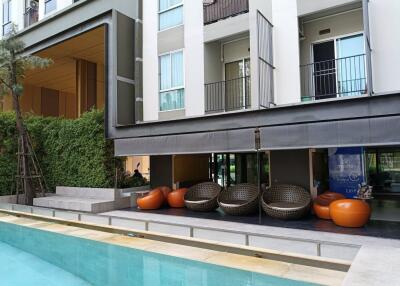 Outdoor seating area adjacent to the pool in front of a residential building