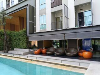 Outdoor seating area adjacent to the pool in front of a residential building