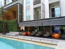 Outdoor seating area adjacent to the pool in front of a residential building