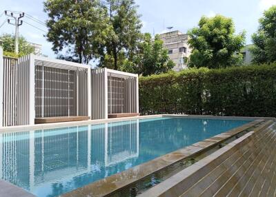 Modern outdoor pool area with cabanas and trees