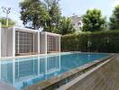 Modern outdoor pool area with cabanas and trees