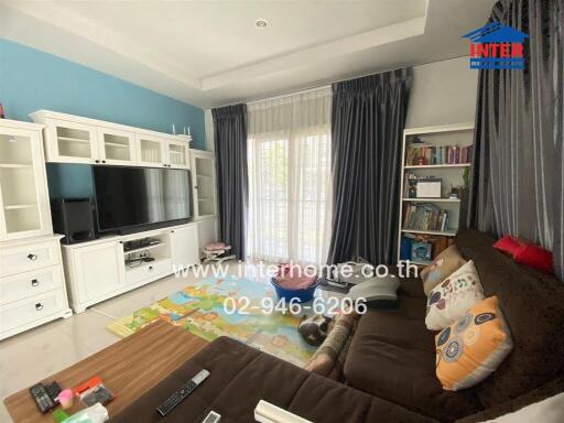 Spacious living room with large windows, a TV unit, sofa, and a play area