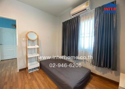 Simple bedroom with a mattress on the floor, a shelf with a mirror, and an air conditioner.