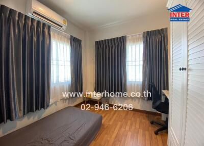 Bedroom with wooden flooring, window drapes, air conditioning, and a desk.