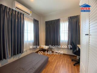 Bedroom with wooden flooring, window drapes, air conditioning, and a desk.