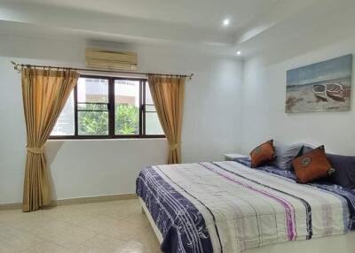 Spacious bedroom with large window, bed, television, and wall art