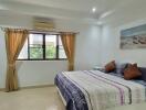 Spacious bedroom with large window, bed, television, and wall art