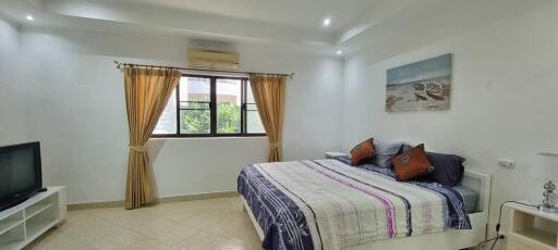 Spacious bedroom with large window, bed, television, and wall art