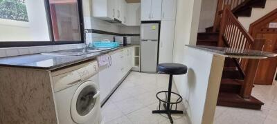 Modern kitchen with appliances and staircase in the background