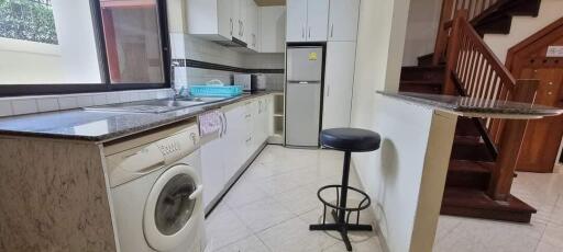 Modern kitchen with appliances and staircase in the background