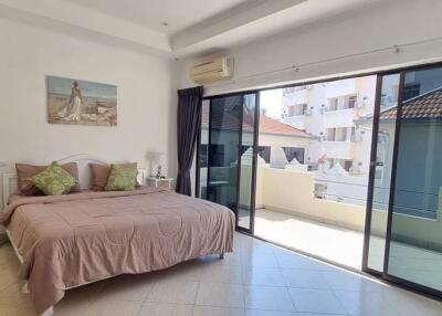 Spacious bedroom with bed, balcony access, and natural light