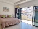 Spacious bedroom with bed, balcony access, and natural light