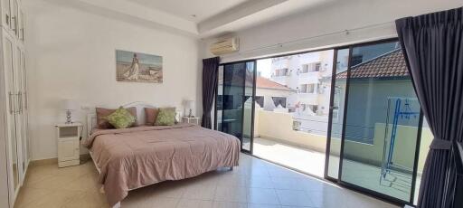 Spacious bedroom with bed, balcony access, and natural light